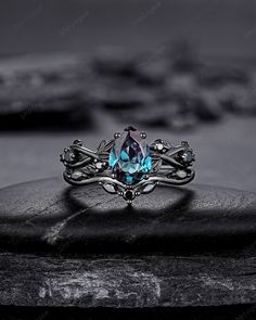 a ring that is sitting on top of a rock and has a blue stone in the middle