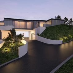 a modern house is lit up at night with green grass on the roof and landscaping around it