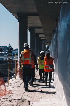 three construction workers walking down the sidewalk