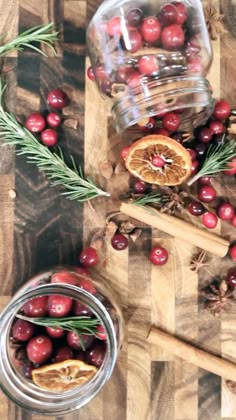 some cranberries and oranges on a cutting board next to a glass jar