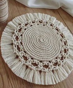 a white round rug with tassels is on the floor next to some yarn