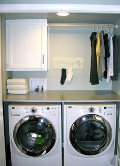 a washer and dryer in a small room with clothes hanging on the rack