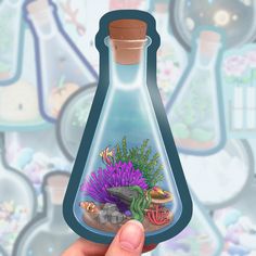 a hand holding up a small bottle with an image of a fish in it and corals inside