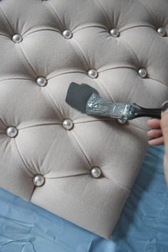 a person using a paint brush on an upholstered bed headboard with pearls