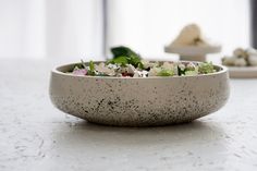 a white bowl filled with salad sitting on top of a counter next to other dishes