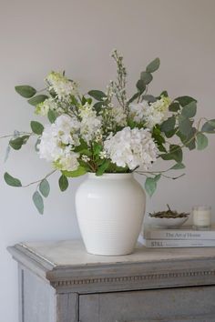 a white vase filled with flowers on top of a table