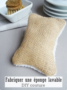 a pillow sitting on top of a table covered in burlap next to plates