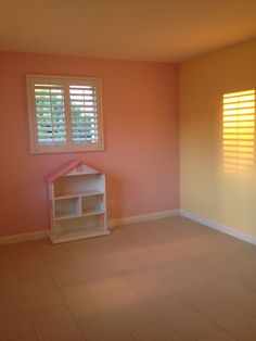 an empty room with pink walls and white shutters