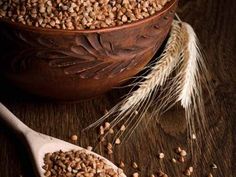 two wooden spoons filled with grain on top of a table