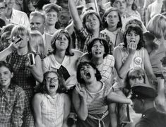 a group of people standing next to each other in front of a crowd with their mouths open