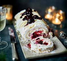 there is a large roll with fruit on it next to some wine glasses and silverware