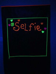 a neon sign that says selfie on the side of a wall in a dark room