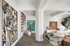 a living room filled with furniture and paintings on the wall