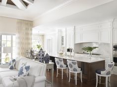 a living room filled with furniture next to a kitchen and dining room table covered in blue and white pillows