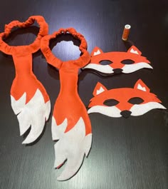 an orange and white fox mask with two other masks next to it on a table