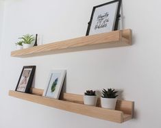 two wooden shelves with plants and pictures on them