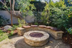 a stone fire pit surrounded by trees and bushes