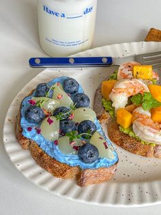 a white plate topped with two pieces of bread covered in fruit and veggies