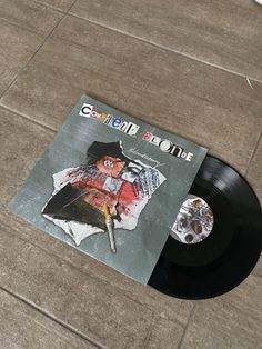 a black record sitting on top of a floor next to a white and gray object