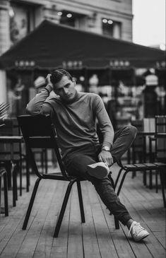 a man sitting on top of a wooden chair next to a table with chairs around him