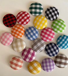 several different colored plaid fabric buttons on a white surface