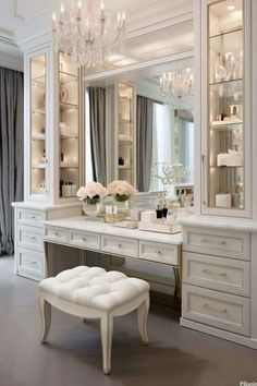 a white dressing room with chandelier, stool and large mirror on the wall