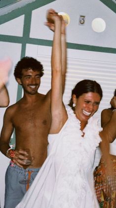 a man and woman are dancing together at a party with their arms in the air