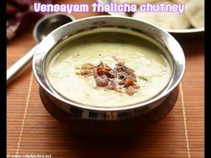 a metal bowl filled with soup on top of a wooden table