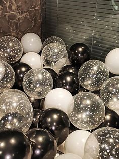 some black and white balloons are in a ball pit with silver stars on the top