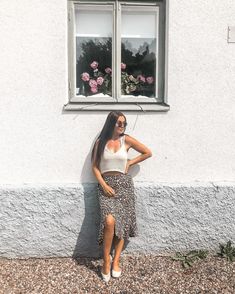 a woman standing in front of a window with her hands on her hips and arms behind her back