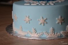 a blue frosted cake with white snowflakes on it