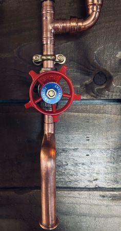 a copper pipe with a red spigot attached to it