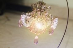 a chandelier hanging from a metal pole with pink and white beads on it