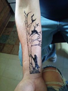 a person with a tattoo on their arm is sitting in front of a tree branch