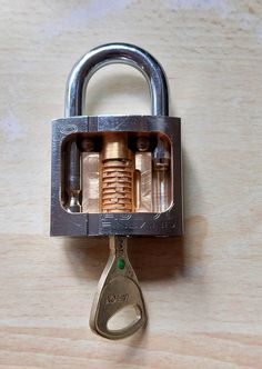 an open padlock with two keys attached to it on a wooden surface and the lock is closed