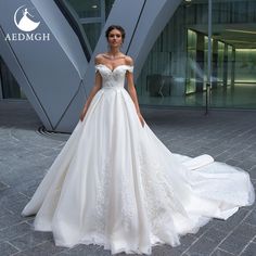 a woman in a white wedding dress standing on a brick floor next to a building