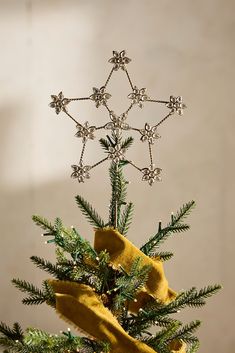 a small christmas tree with a star decoration on it's top and yellow ribbon