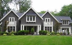 a large gray house with white trim on the front and side windows, grass in front