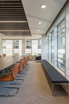 an empty conference room with long tables and leather chairs in front of large windows on the wall