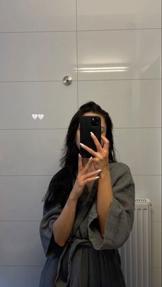 a woman taking a selfie in front of a bathroom mirror with her cell phone