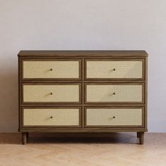 an old dresser with wicker drawers on the top and bottom, against a white wall