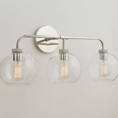 three light bathroom fixture with clear glass globes and chrome finish, on a white wall