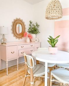 a white table and chairs in a room with pink walls, wooden floors and a mirror on the wall