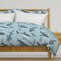 a bed with two pillows on top of it and some birds printed on the comforter