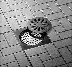 a black and white photo of a drain on the ground with a grate in it