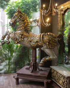 a horse statue sitting on top of a wooden table next to a mirror and chandelier