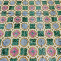 an artistic tile design with pink flowers on green and yellow tiles, in the middle of a floor