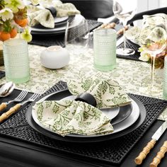 the table is set with black and white plates, silverware, and green napkins