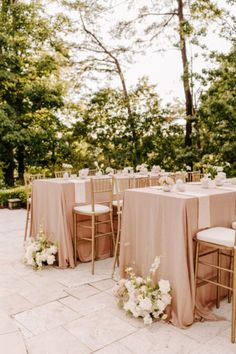 the tables are set up with pink linens and gold chairs for an outdoor wedding