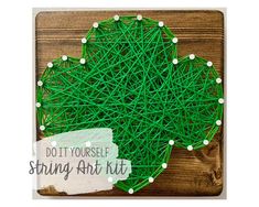 the string art kit is made with green yarn and white pins on top of it